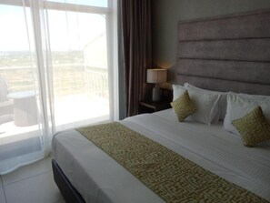 Une chambre d’hôtel avec un grand lit, une table de chevet avec une lampe et une vue sur l’extérieur grâce à une porte coulissante.