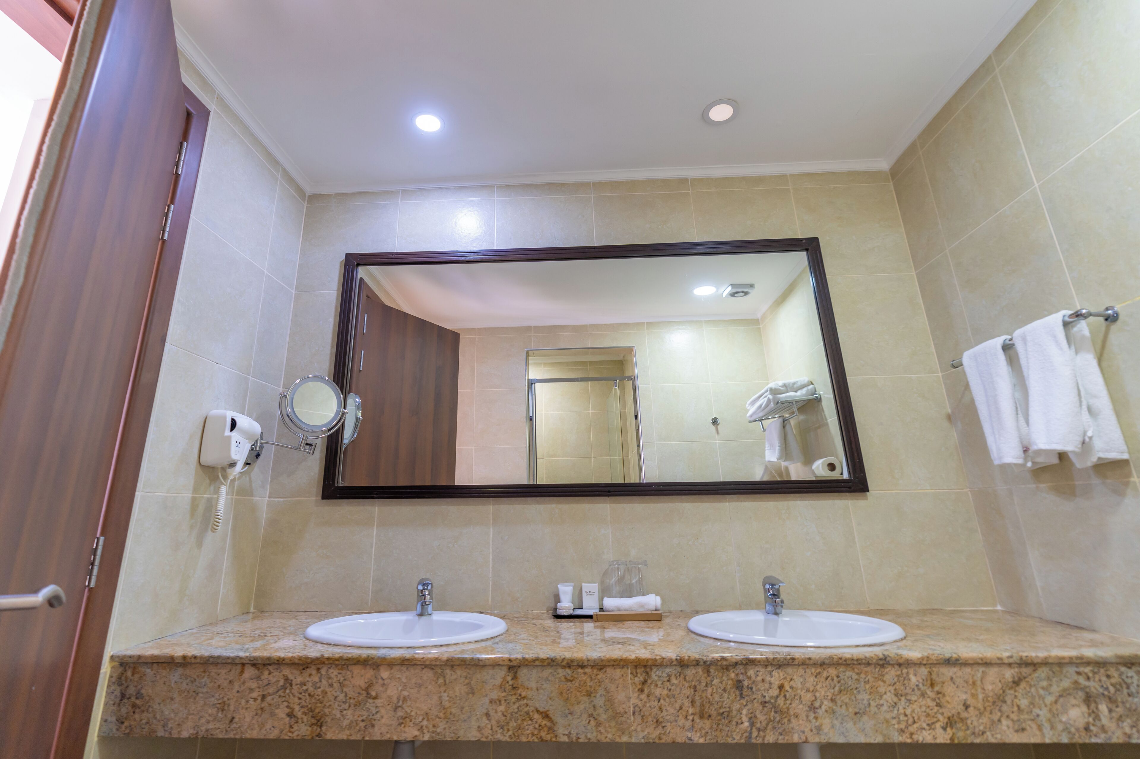 A bathroom with two sinks, a large mirror, and a towel rack.
