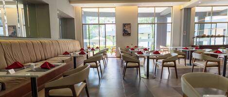A modern restaurant with a long counter, booths, and high tables.