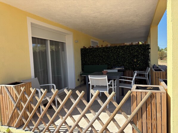 Une terrasse extérieure avec une table et des chaises, un barbecue et une clôture en bois.