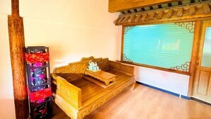 A traditional wooden sofa with a cushion, a wooden cabinet with a red and black design, and a window with a blue shutter. - Wu Suo · Li Ziyuan (Lijiang Old Town Mufu Hotel) (Lijiang)