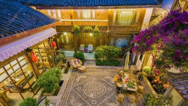 A traditional courtyard with a tiled roof, a central seating area, and surrounding greenery. - Wu Suo · Li Ziyuan (Lijiang Old Town Mufu Hotel) (Lijiang)