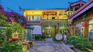A traditional courtyard with a wooden building, a decorative stone pattern on the ground, and a hanging lantern. - Wu Suo · Li Ziyuan (Lijiang Old Town Mufu Hotel) (Lijiang)