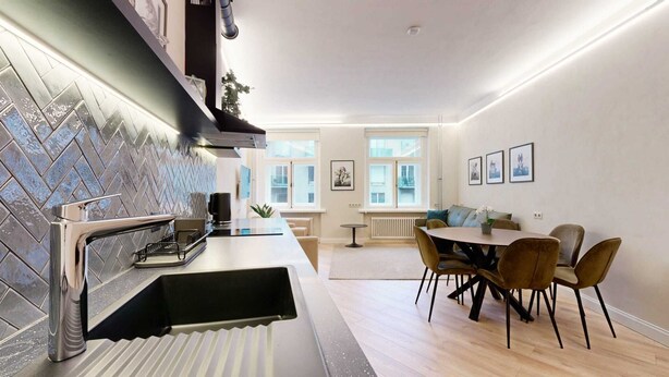 A modern kitchen with a herringbone tile backsplash, a stainless steel range hood, and a built-in dishwasher.