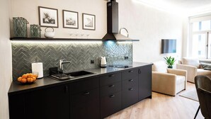 A modern kitchen with a herringbone tile backsplash, a black countertop, and a built-in sink.