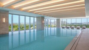 Una piscina interior moderna con grandes ventanales y vistas a la ciudad.