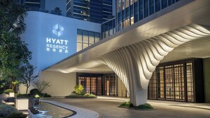 Entrada del hotel Hyatt Regency con un diseño moderno, un elemento acuático y una fachada bien iluminada.