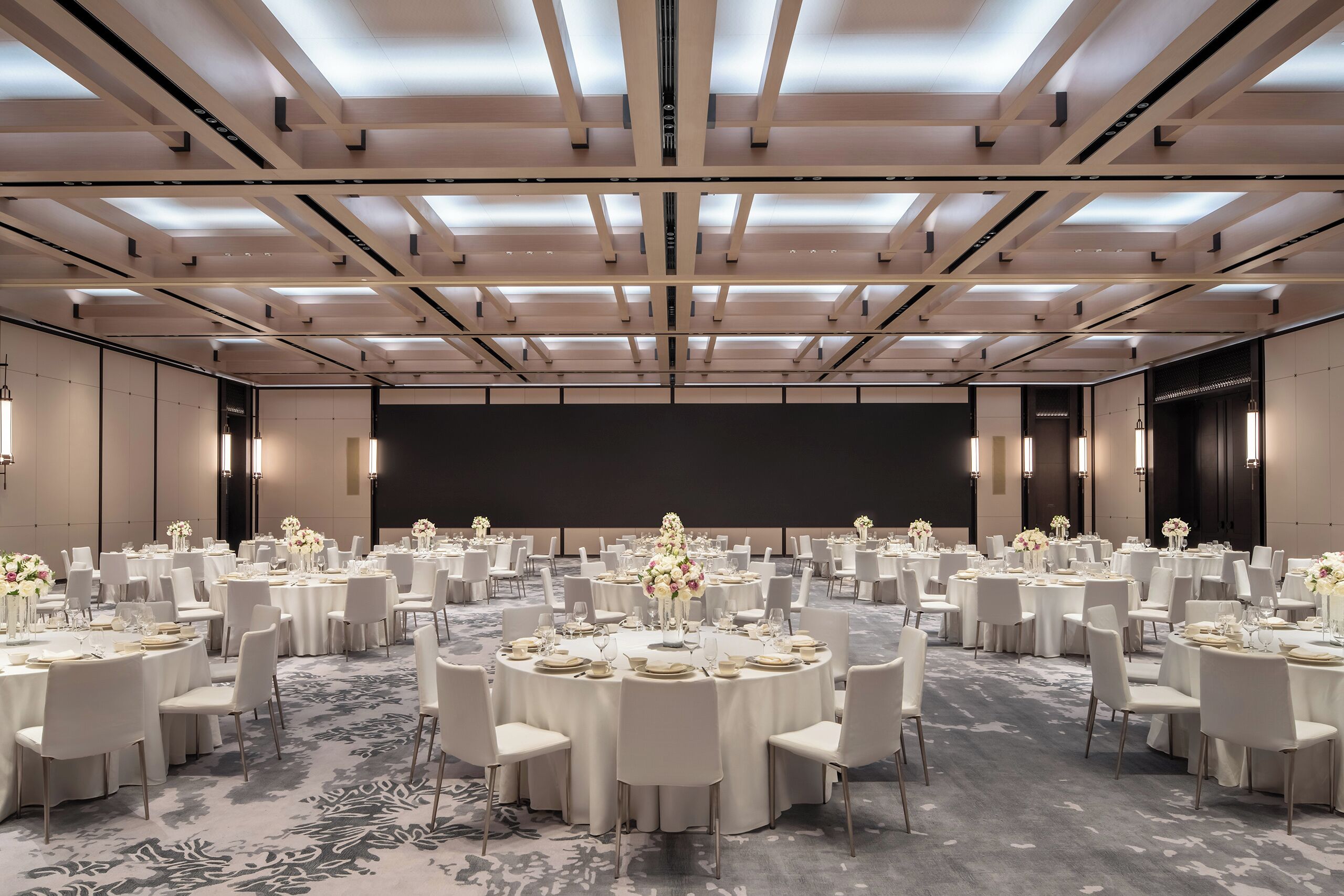 A conference room with round tables, white chairs, and floral centerpieces.