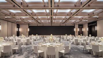 A conference room with round tables, white chairs, and floral centerpieces.