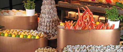A seafood display with various types of shellfish and crustaceans, including oysters, clams, and crabs, arranged in copper containers.
