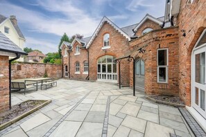 A courtyard with a brick building, stone flooring, and outdoor seating.