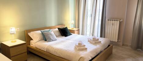 A neatly made bed with pillows, a bedside lamp, and a nightstand with a lamp.