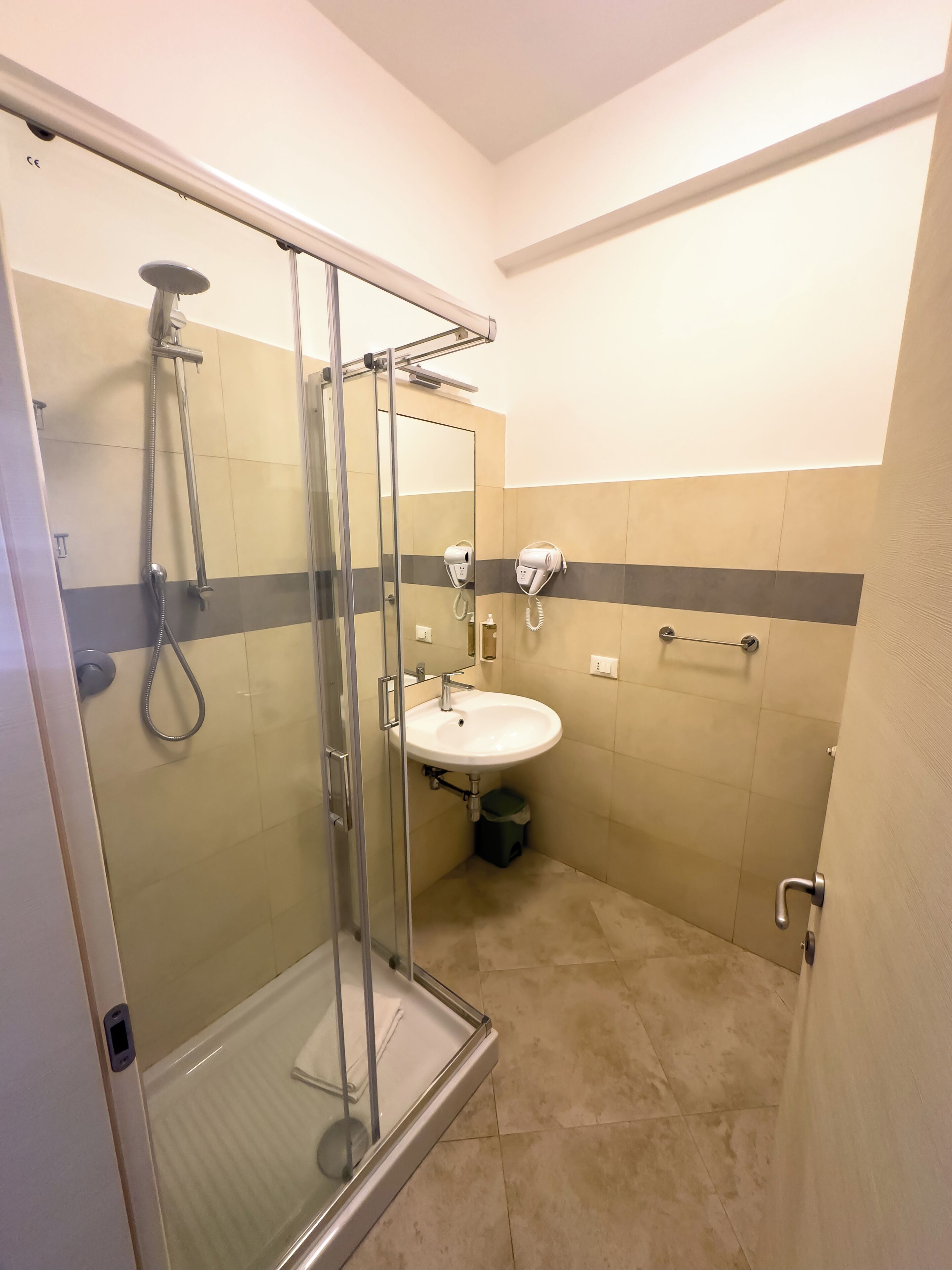 A modern bathroom with a glass-enclosed shower, a sink, and a towel rack.