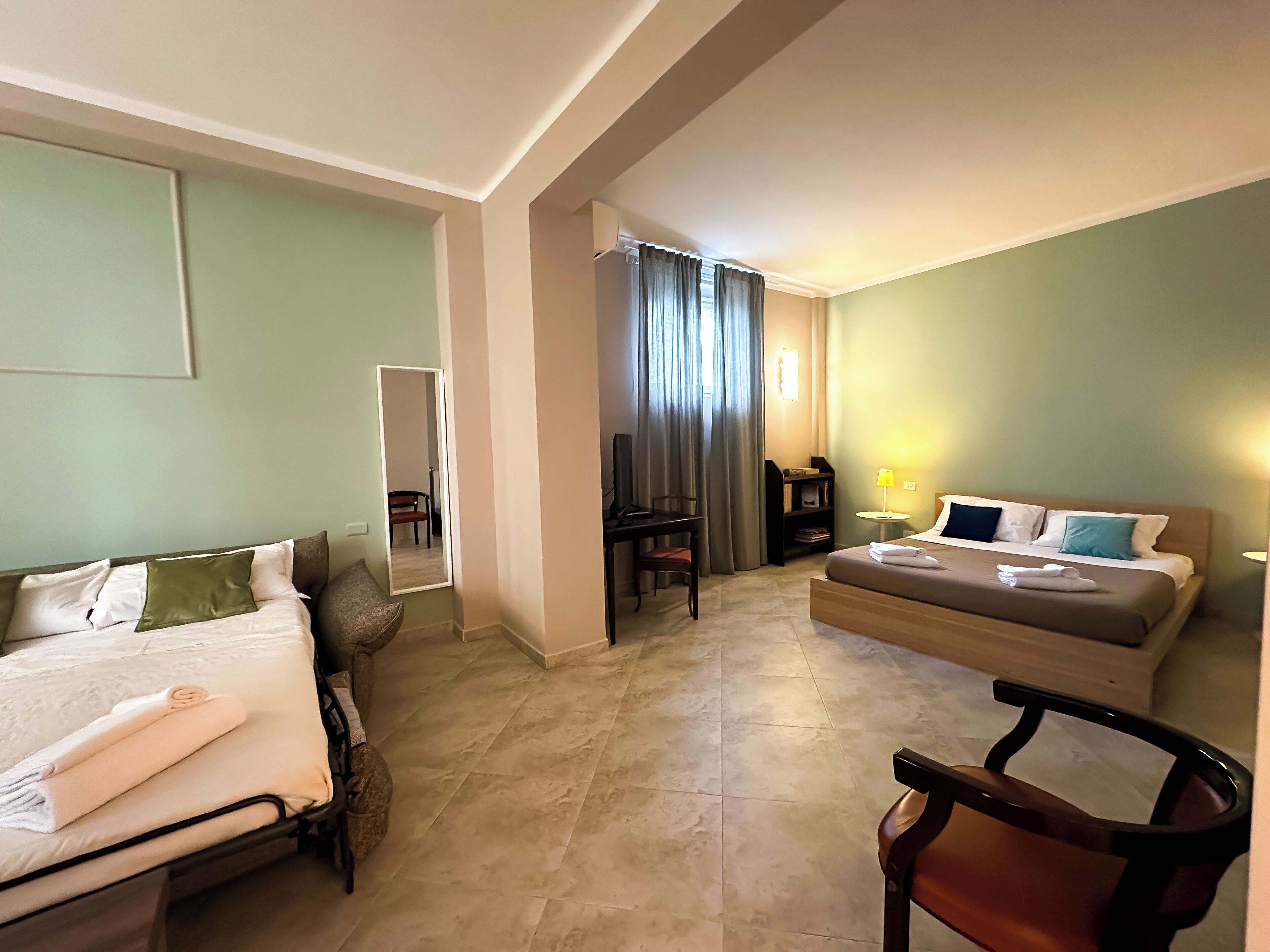 Une chambre d’hôtel avec un lit, une chaise, un bureau et un miroir.