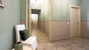 A hallway with a white bench, a vase, and a door. - SWEET HOME COSSERIA (Florence)