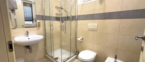 Ein Badezimmer mit Duschkabine, Waschbecken, Toilette und Bidet.