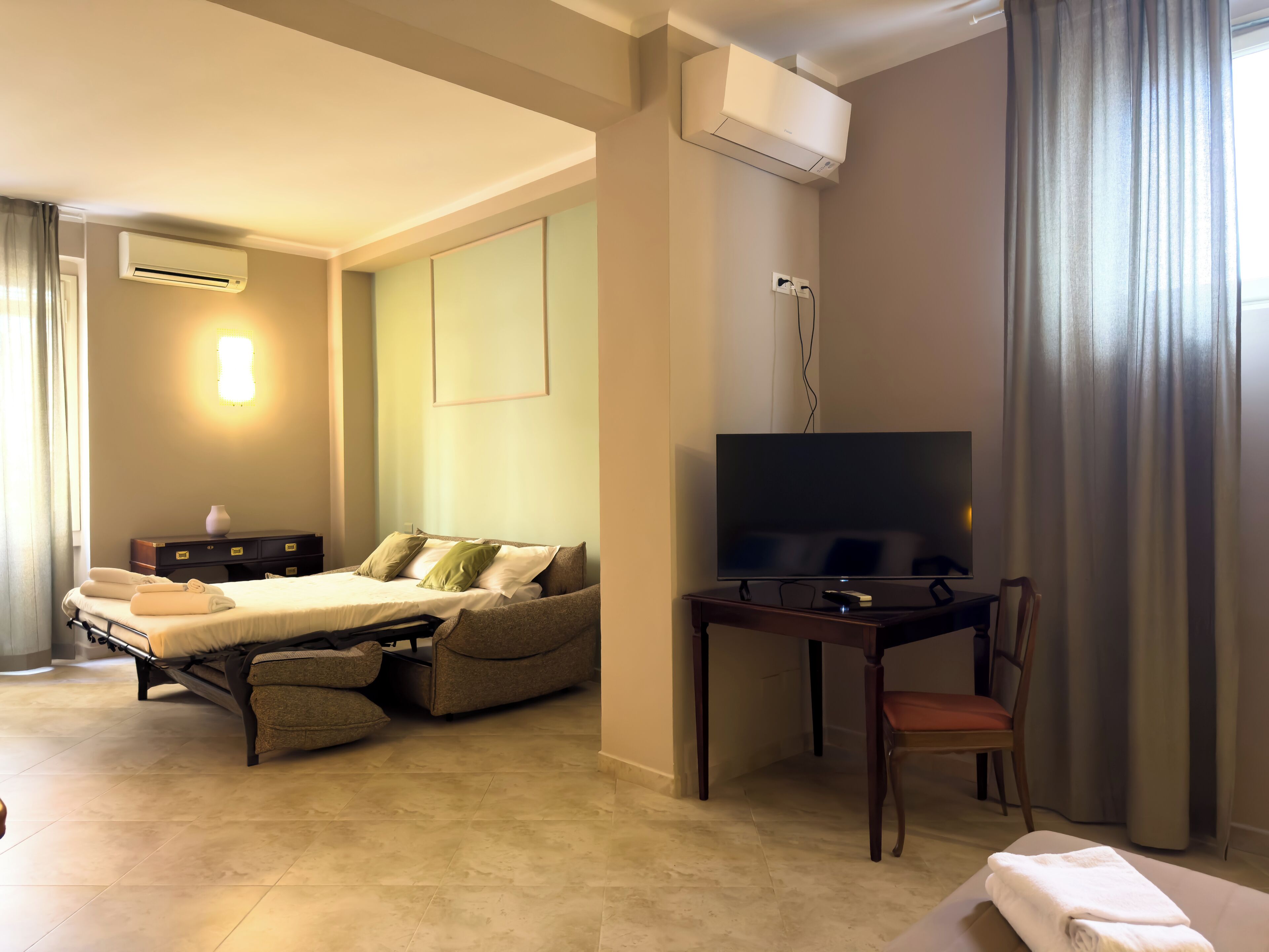 A hotel room with a bed, a TV, a desk, and a chair.