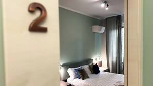 A bedroom with a bed, a nightstand, a wall-mounted lamp, and a window with curtains. - SWEET HOME COSSERIA (Florence)