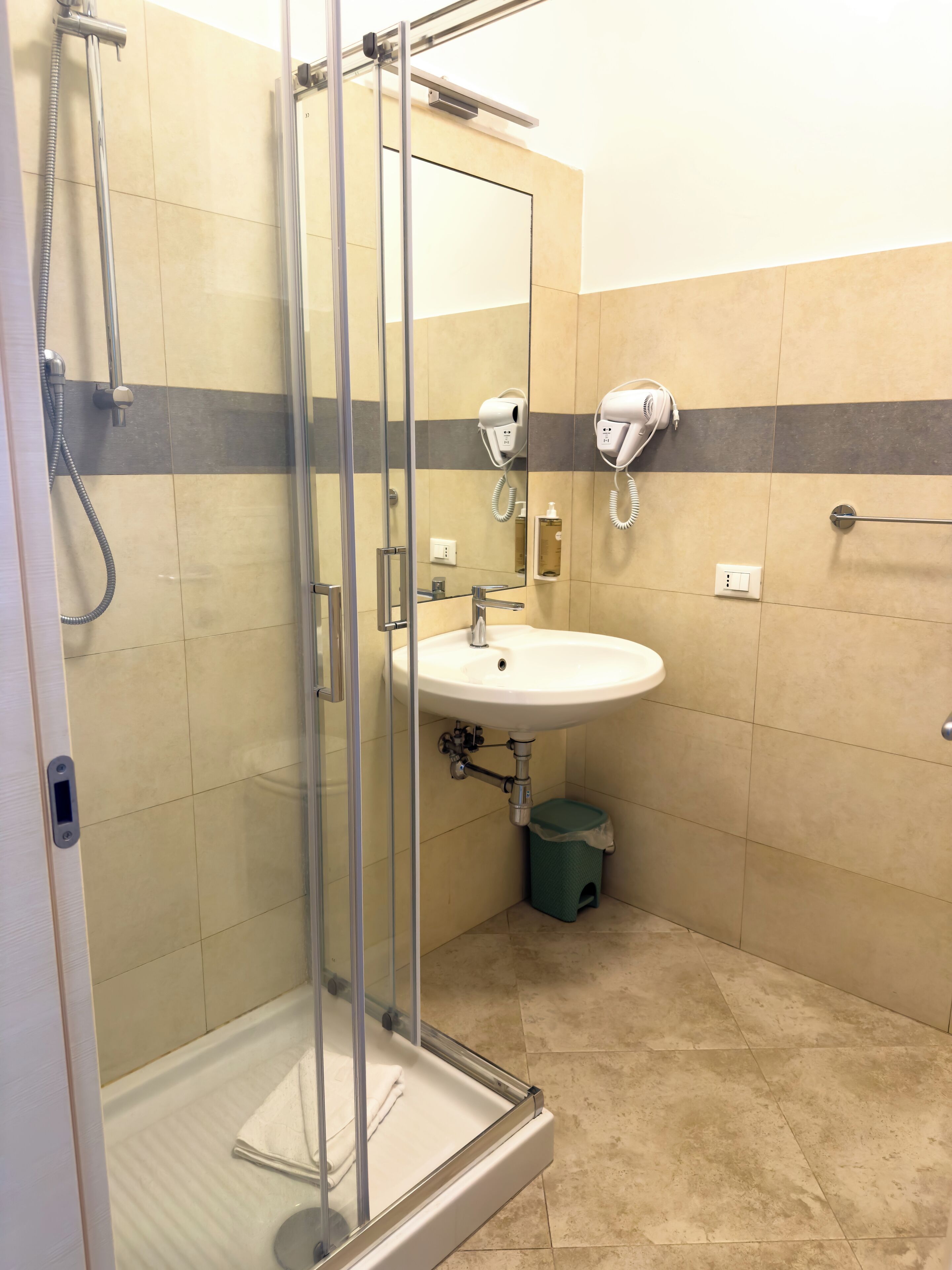A modern bathroom with a glass-enclosed shower, a sink, and a mirror.