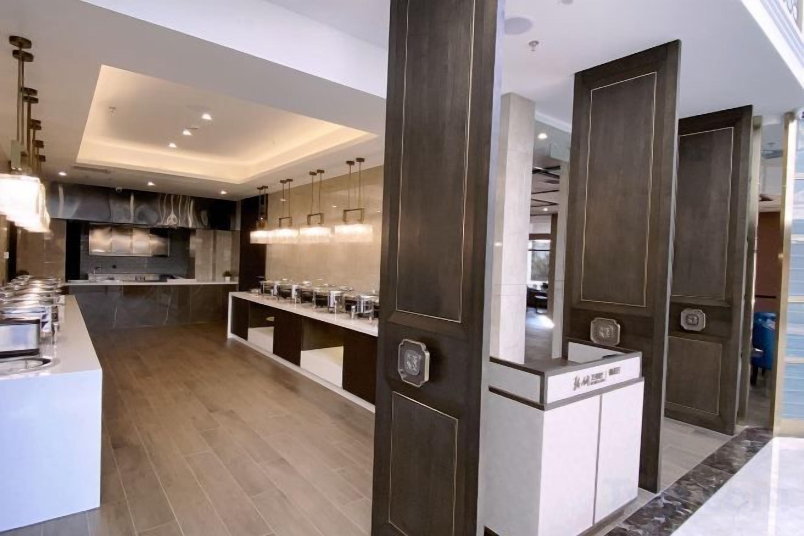 Una cocina moderna con una isla central, puertas de madera oscura y un horno empotrado.