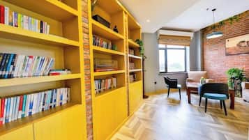 A room with a large bookshelf, a dining area with two chairs, and a brick wall.