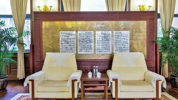 A traditional room with two sofas, a small table, and a decorative wall with calligraphy.