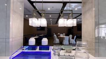 Un hall de hotel con mostrador de recepción, zona de estar y comedor.