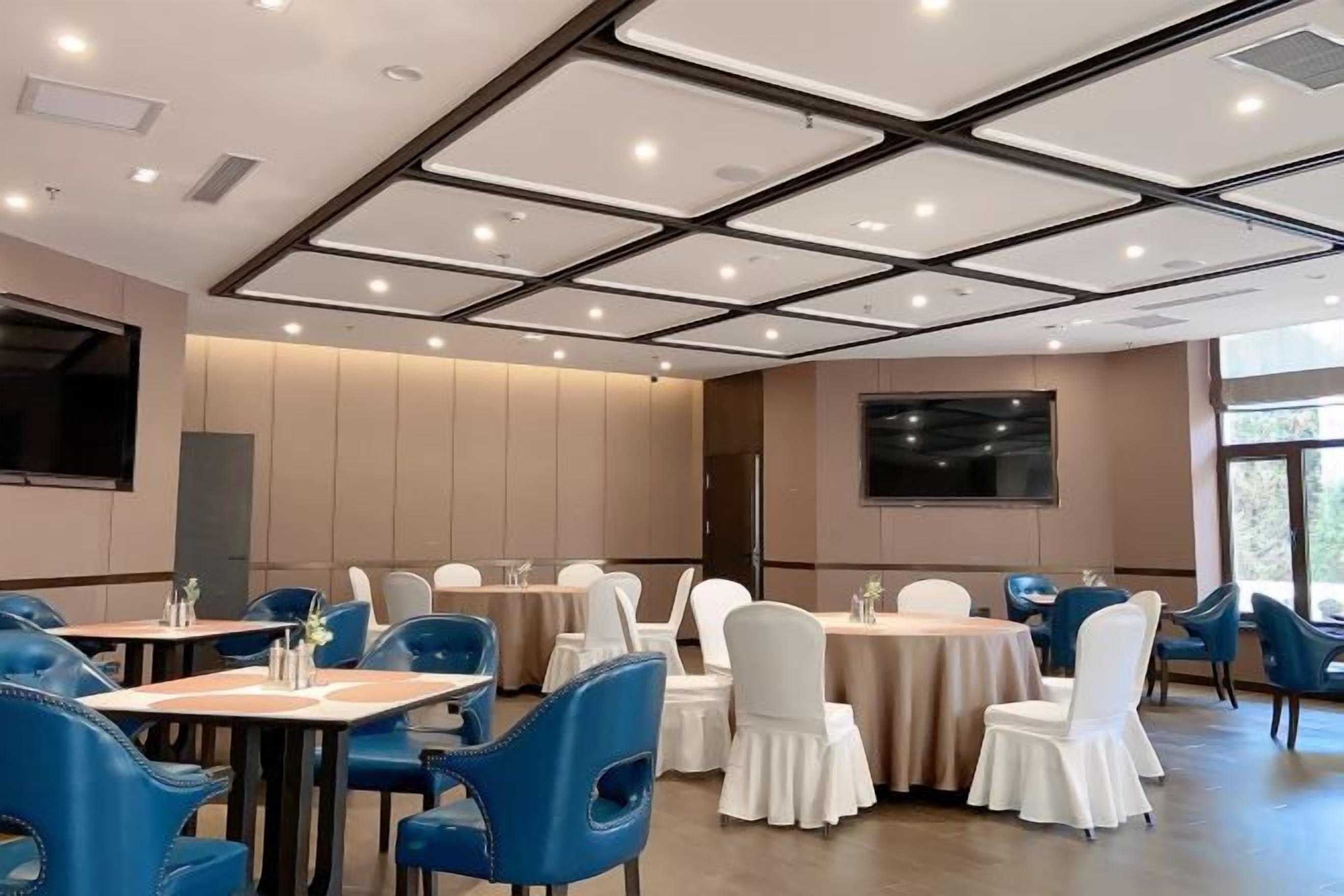 A conference room with tables and chairs, a large screen, and a view of the outdoors.