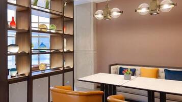 A dining area with a table and chairs, a bookshelf with decorative items, and pendant lighting.