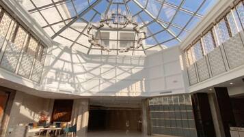 A spacious atrium with a glass ceiling, a chandelier, and a seating area.