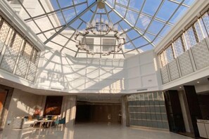 A spacious atrium with a glass ceiling, a chandelier, and a seating area. - Dongshan Hotel (Anshan)