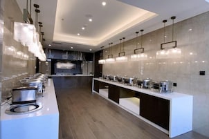 Una cocina moderna con una barra alargada, varios dispensadores de alimentos e iluminación colgante.