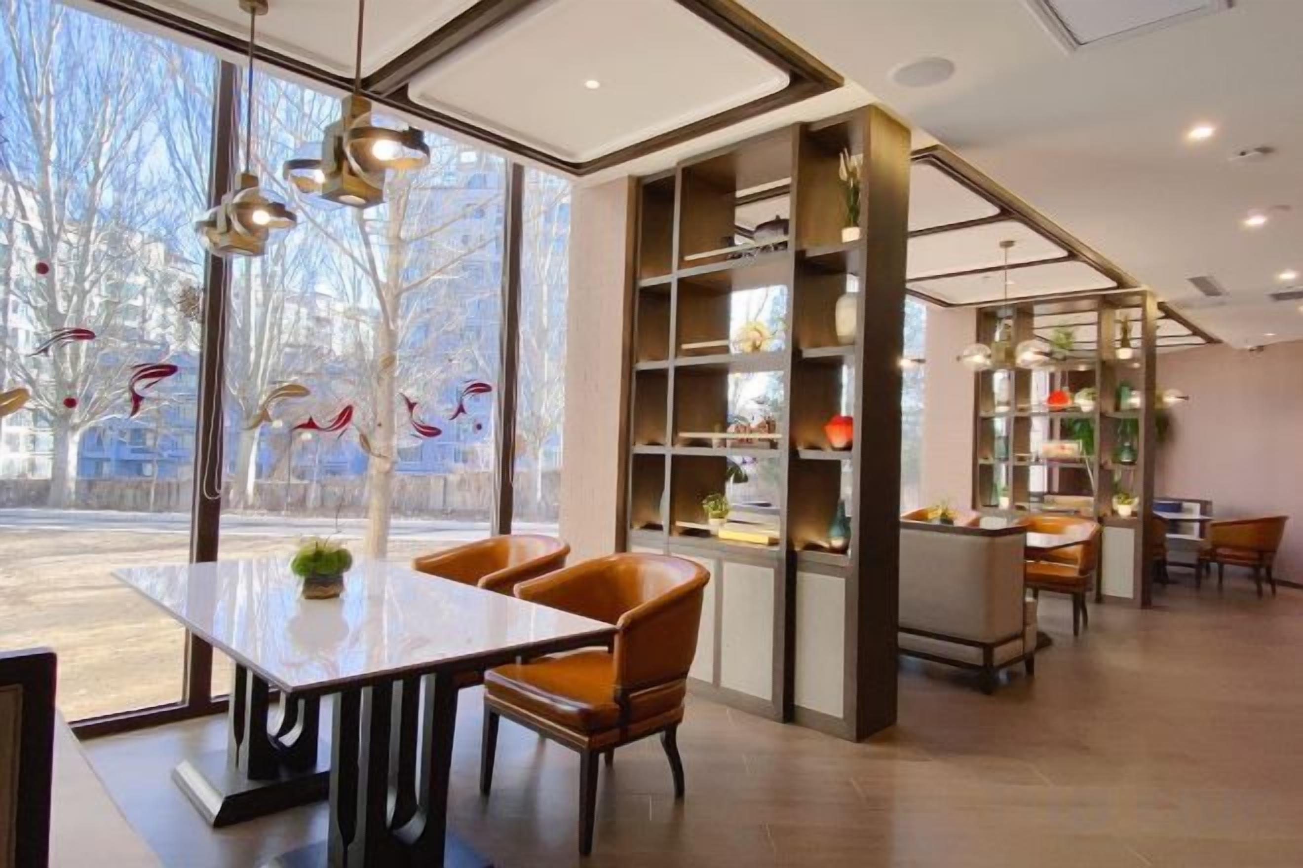 Un intérieur moderne comprenant un coin repas, des étagères et une vue dégagée grâce à de grandes fenêtres.