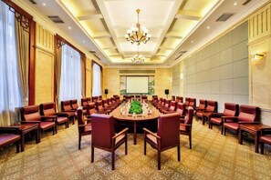A conference room with a large oval table surrounded by chairs, a projector screen, and a chandelier. - Dongshan Hotel (Anshan)