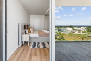 A bedroom with a bed, bedside table, lamp, and a view of the city through large windows. - GuestReady - Beautiful getaway in Gaia (Vila Nova de Gaia)