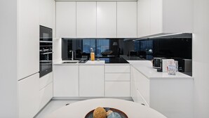 Een moderne keuken met witte kasten, een inbouwoven en een zwart fornuis.