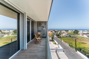 A balcony with a table and chairs, overlooking a residential area and the sea. - GuestReady - Beautiful getaway in Gaia (Vila Nova de Gaia)