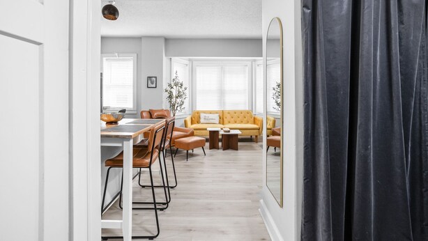 Een moderne woonkamer met een bank, salontafel en stoelen. Er is een eethoek met een tafel en stoelen.