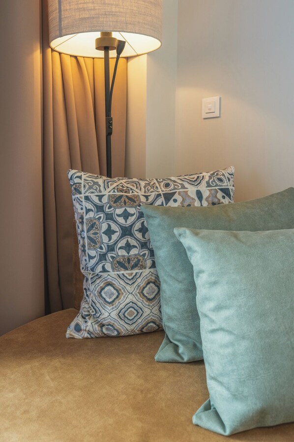 A room with a sofa, patterned pillows, a lamp, and a curtain. - STUDENT EXPERIENCE MADRID POZUELO (Pozuelo de Alarcon)