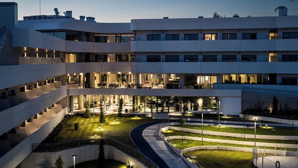 A modern building with multiple floors, outdoor seating areas, and a well-lit courtyard. - STUDENT EXPERIENCE MADRID POZUELO (Pozuelo de Alarcon)