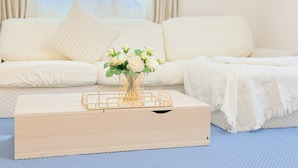 Un salon moderne avec un canapé blanc, une table basse en bois et un vase rempli de fleurs blanches.