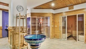 A sauna room with a large blue ceramic basin, wooden walls, and a wooden ceiling.