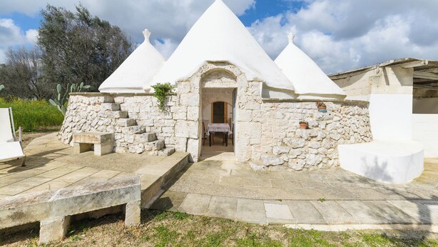 A stone building with a white roof and a central doorway. - Trullo Puspo by Wonderful Italy (Carovigno)