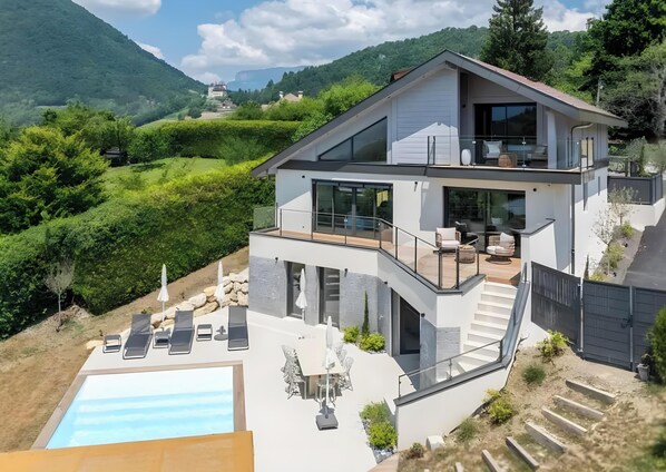 A modern two-story house with a balcony, a pool, and a view of the surrounding hills. - Villa 'Near Village and Lake' with Lake View, Wi-Fi and Air Conditioning (Talloires-Montmin)