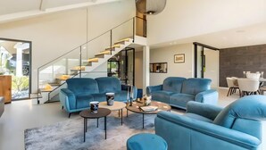 Un salon moderne avec des canapés bleus, une table basse et un escalier menant à un niveau supérieur.