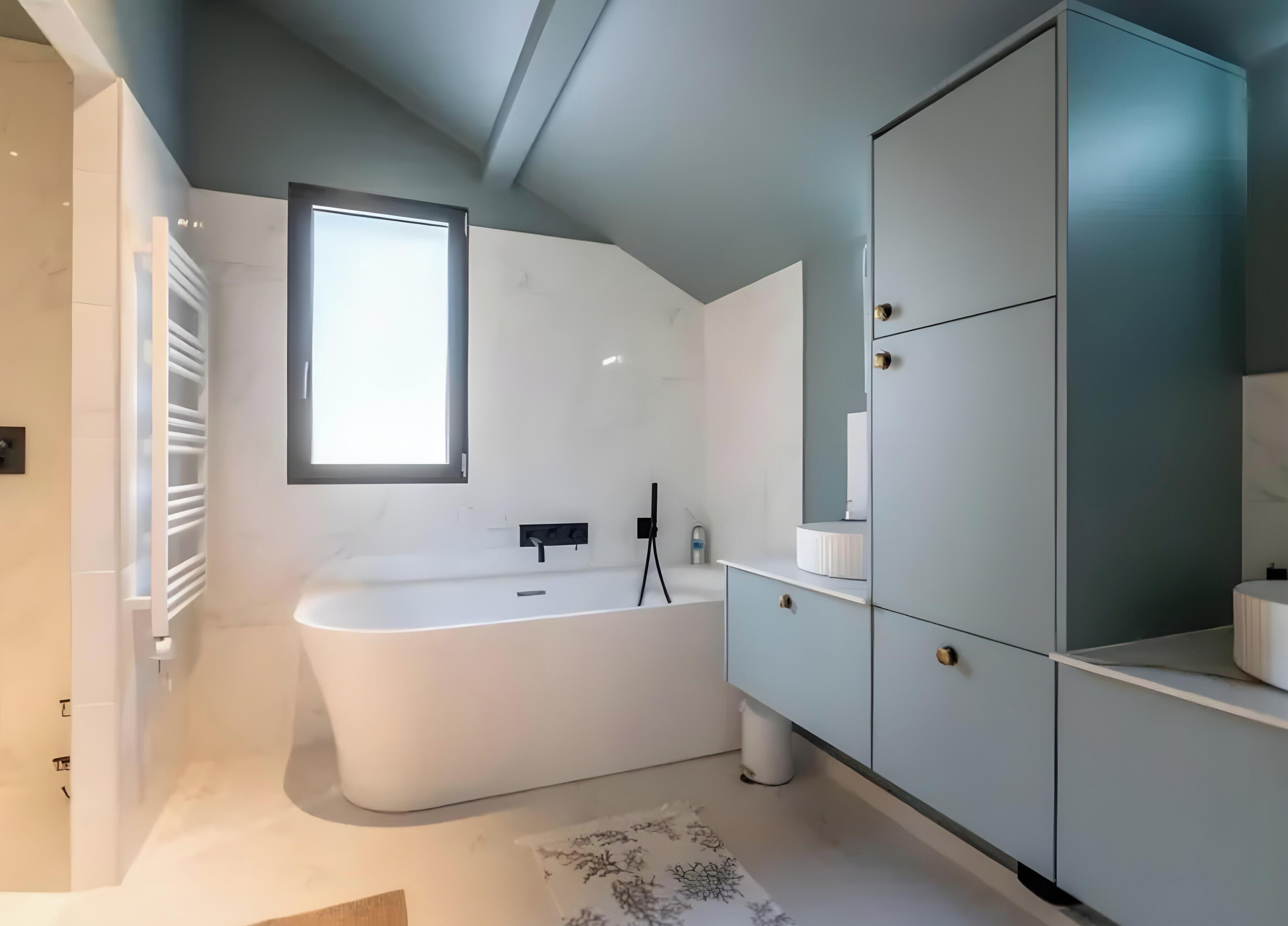 Une salle de bain moderne avec une baignoire sur pieds, un grand miroir et un meuble encastré.