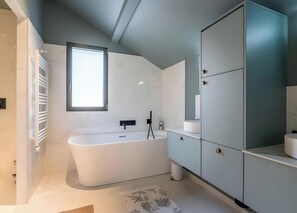 A modern bathroom with a freestanding bathtub, a large mirror, and a built-in cabinet. - Villa 'Near Village and Lake' with Lake View, Wi-Fi and Air Conditioning (Talloires-Montmin)