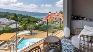 Un balcon avec une piscine, des meubles en osier et une vue sur un lac et des maisons.