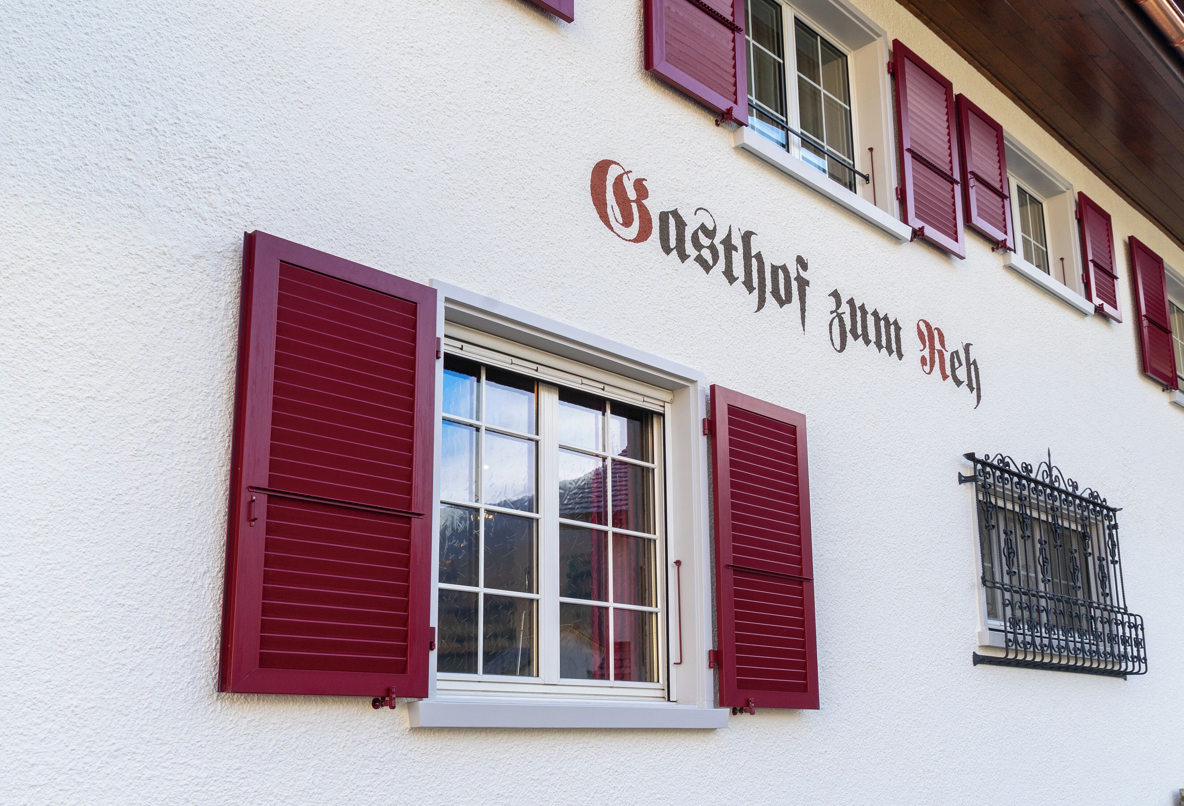 A building with red shutters and a sign that reads "Gasthof zum Reh".