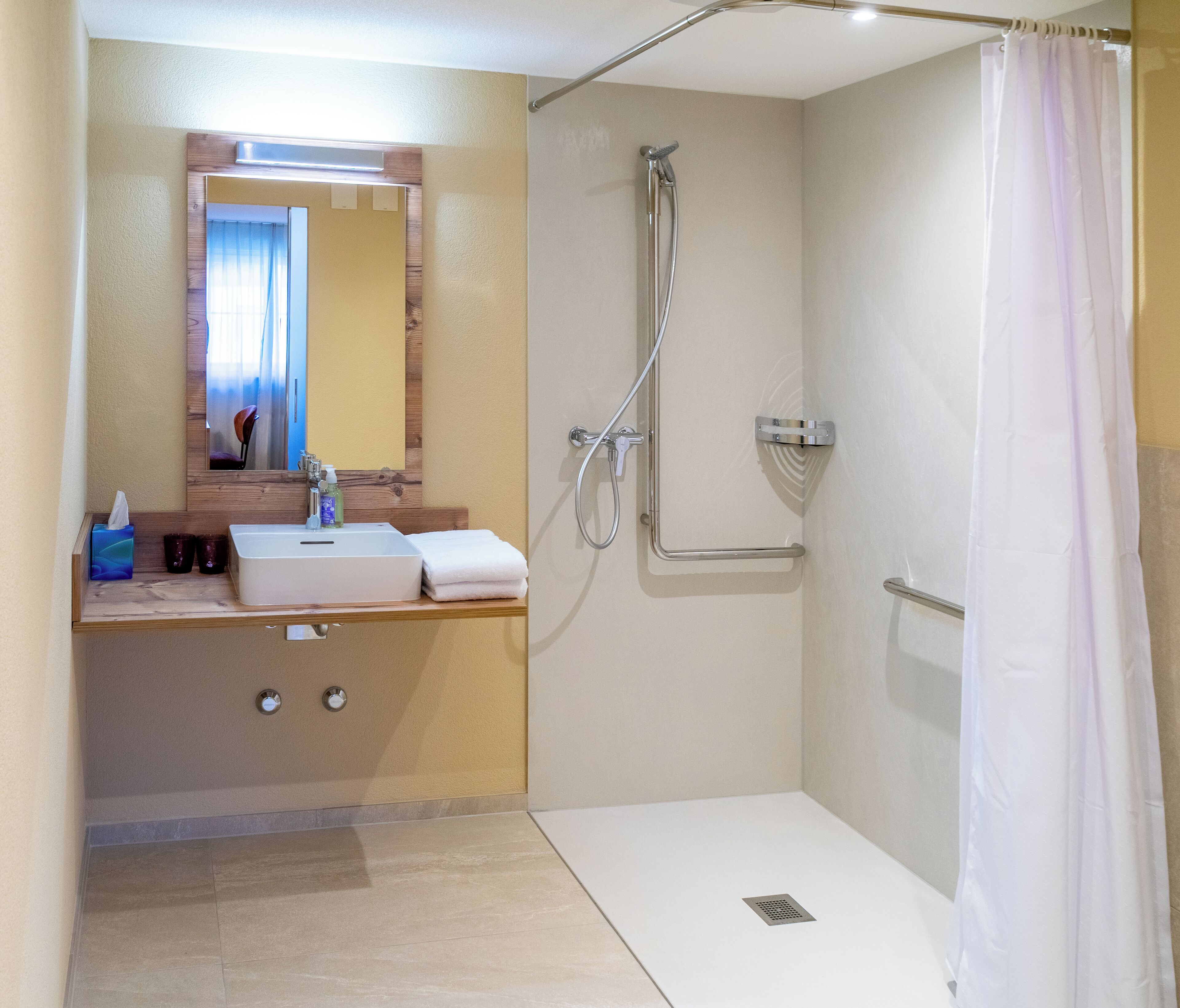 A modern bathroom with a shower, a sink, and a mirror.